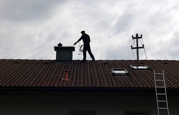 Technician sweeping a brick chimney on a Hanover home